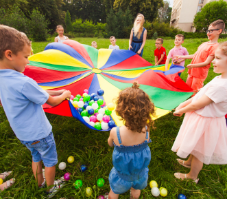 A picture of the children playing with a colourful parachute. 