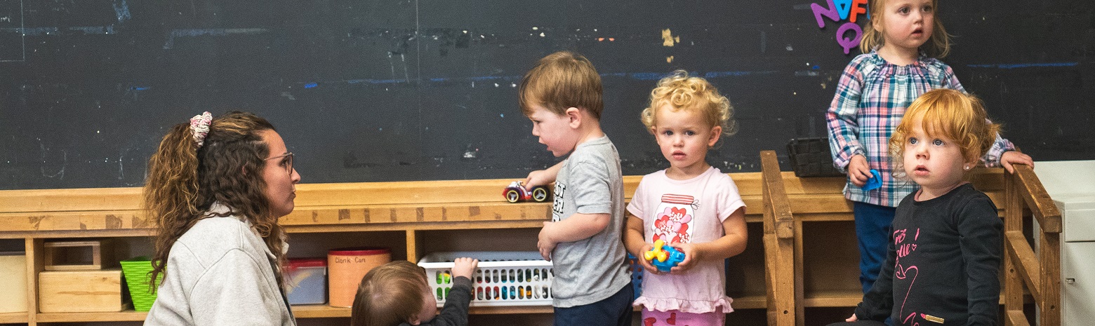 A photo of an Early Childhood Educator and some toddlers.