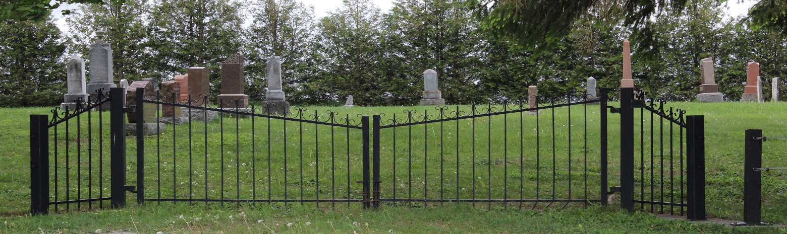 Black iron gate with tombstones in background 