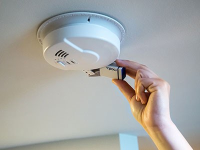 Hand replacing a battery in a smoke alarm 