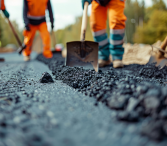 A picture of workers spreading fresh asphalt on the road.