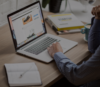 A picture of a man scrolling on a laptop.