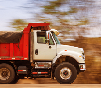 Red & White Dump Truck driving on gravel raod