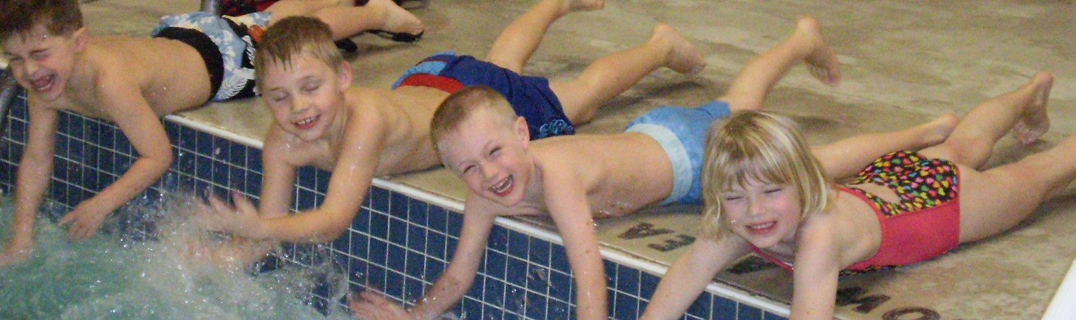 children splashing in a pool from the pool deck