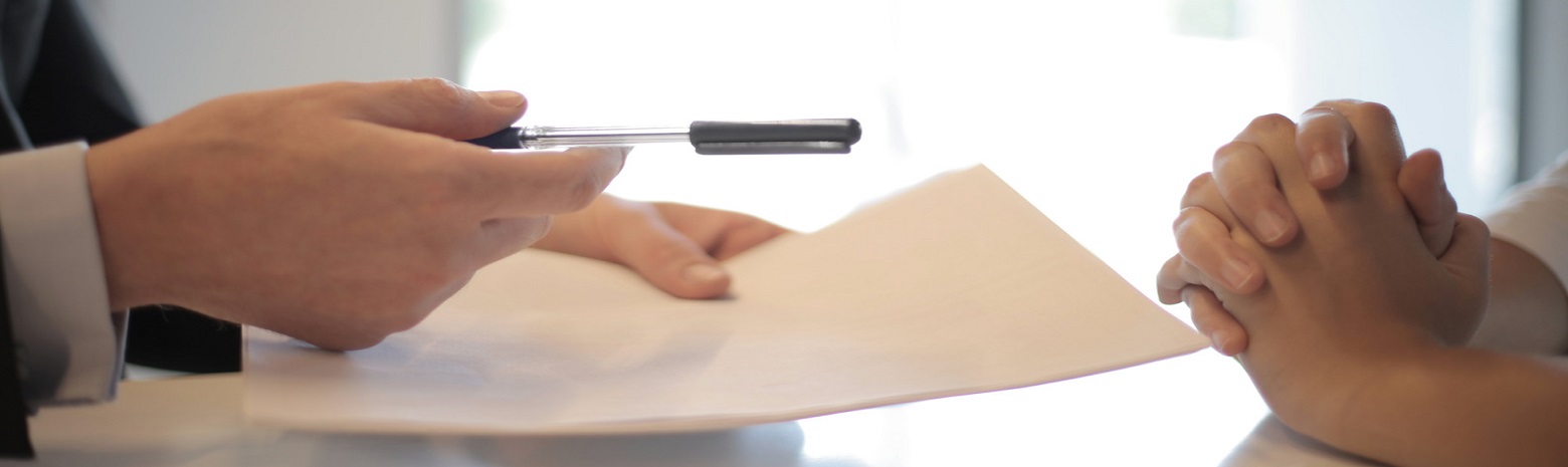 Man handing woman a pen to sign