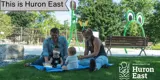 [A picture of two women with their two children sitting on the grass in front of the Seaforth Splash Pad.]